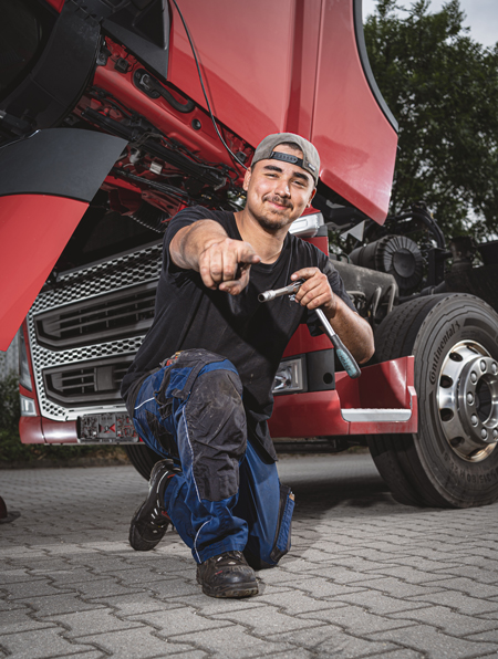 Mitarbeiter kniet vor LKW